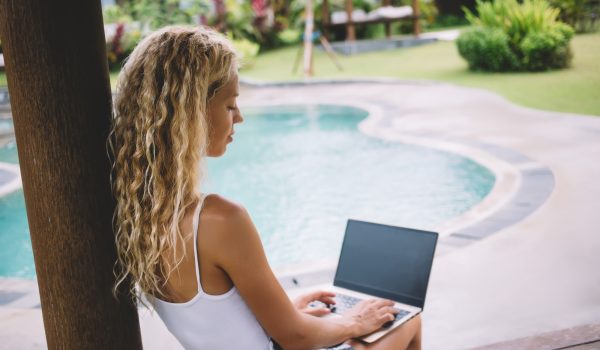 young-woman-using-laptop-in-park-near-swimming-poo-2024-05-14-17-49-25-utc